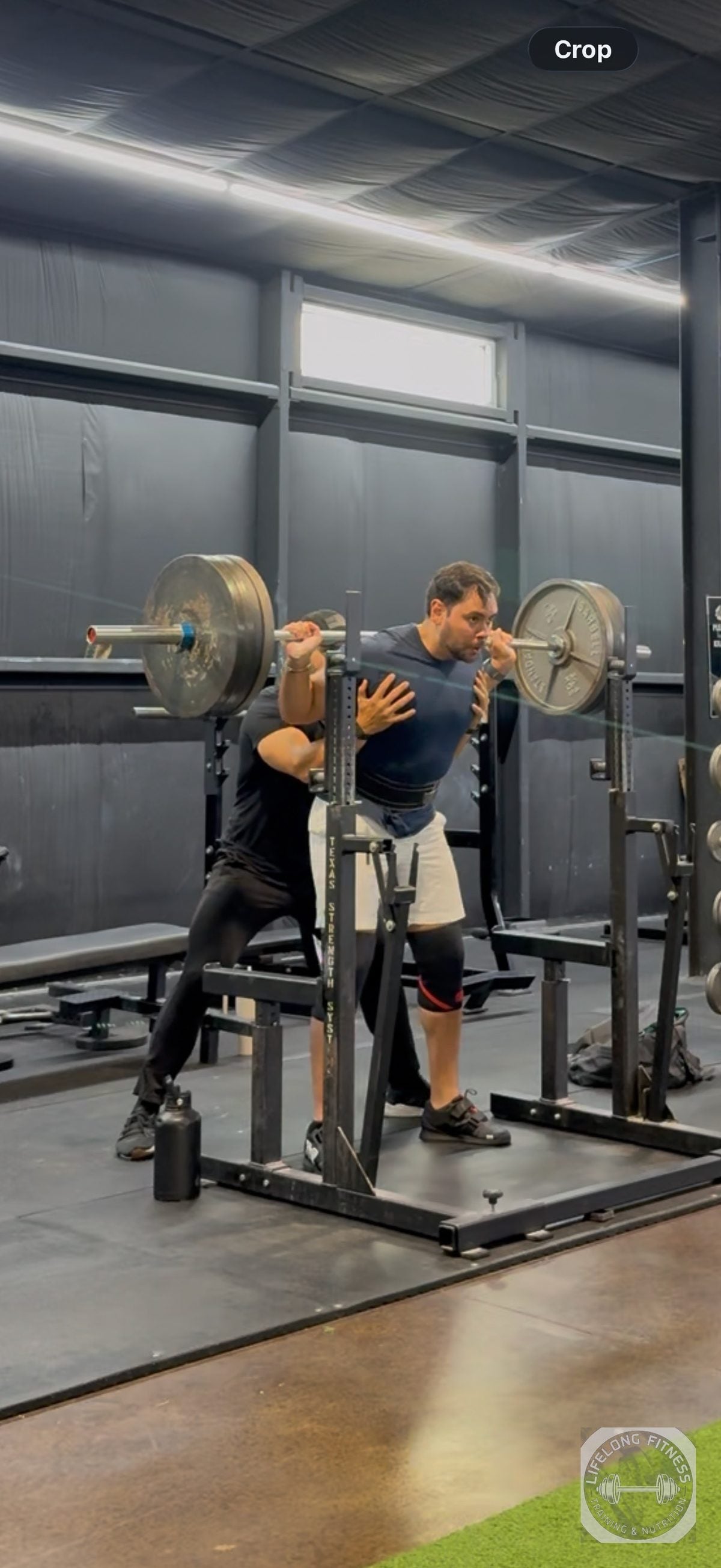 Coach Ozzy spotting a client barbell squat at Rise Gym