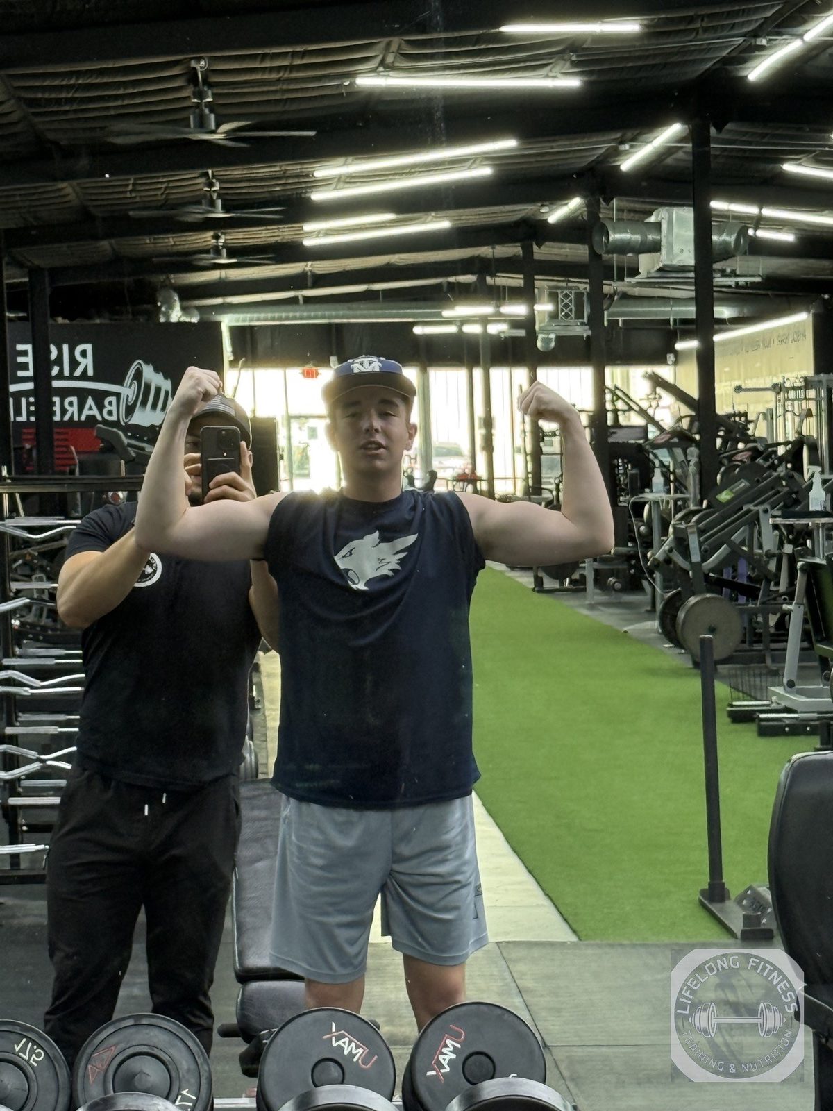 Client flexing double biceps while Ozzy films