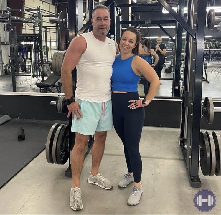 Two clients posing together at the gym